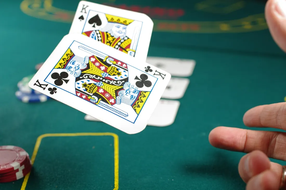 Seseorang memegang kartu remi di meja poker dengan tumpukan chip